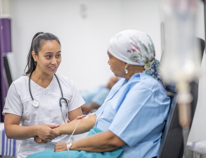 Pflegekraft im Gespräch mit Patientin während einer Infusion