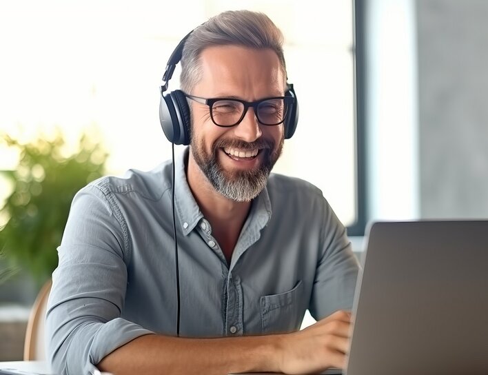 Mann mit Brille und Kopfhörern sitzt entspannt an seinem Laptop