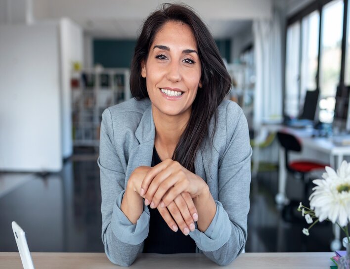 Freundliche Frau im grauen Blazer in einem modernen Büro