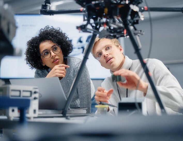 Titelbild Master Mechatronik Eine Frau und ein Mann analysieren gemeinsam ein technisches Gerät in einem modernen Arbeitsumfeld.
