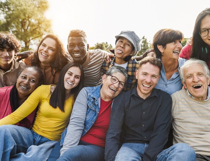 Menschen unterschiedlicher Generationen vereint Gruppe von Menschen verschiedener Altersgruppen und Herkunft, die im Freien zusammen lachen und Positivität ausstrahlen.