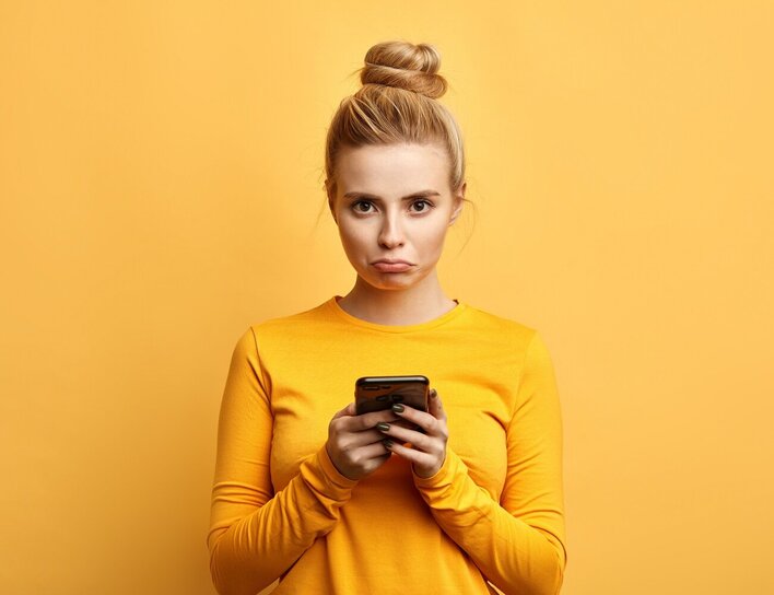 Symbolbold - Frau mit Smartphone und traurigem Blick