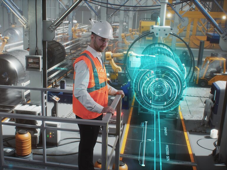 Ein Mann mit weißem Schutzhelm und orangefarbener Warnweste steht in einer Industriehalle und überwacht eine Maschine, die mit einer digitalen, holografischen Darstellung visualisiert wird.