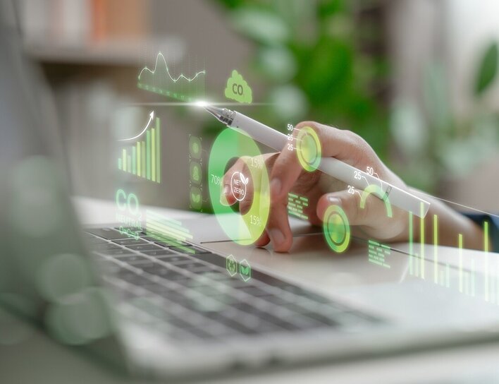 Master Mechatronik Spezialisierung Nachhaltigkeit Eine Hand bedient mit einem Stift ein digitales Dashboard mit Nachhaltigkeits- und CO₂-Daten auf einem Laptop.